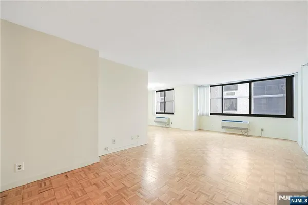 a view of an empty room with a window and cabinet