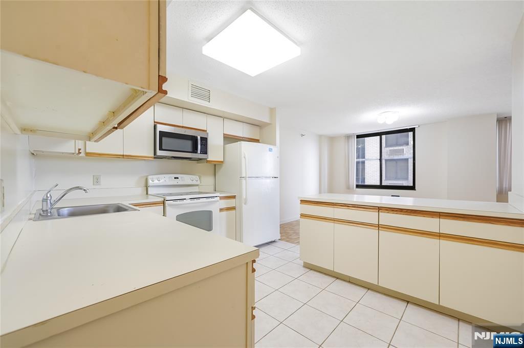 316 Prospect Avenue, Unit 3D Hackensack, NJ 07601 - Photo 16 of 20 a kitchen with a stove a sink and a microwave