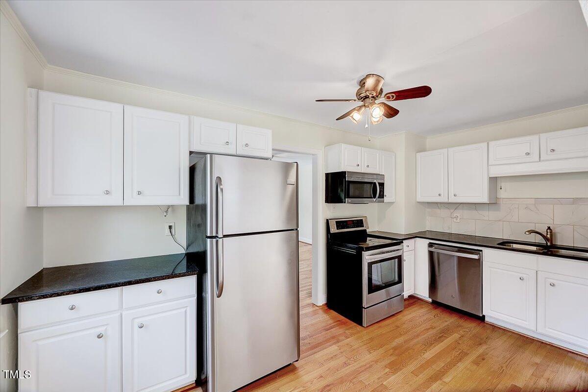 829 Colleton Road Raleigh, NC 27610 - Photo 11 of 27 a kitchen with stainless steel appliances a sink a refrigerator a stove a microwave and cabinets
