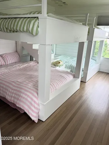 a view of a bedroom with wooden floor and windows