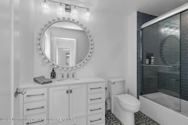 a bathroom with a toilet sink vanity granite and shower