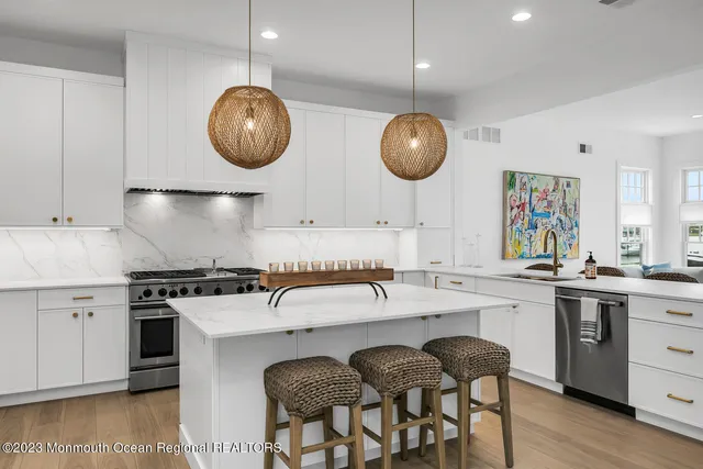 a kitchen with stainless steel appliances granite countertop a stove a sink a dining table and chairs with wooden floor