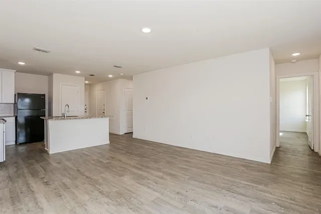 a view of kitchen with refrigerator and white cabinets