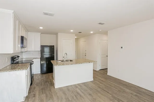 a living room with a sink wooden floor and a refrigerator