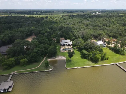 an aerial view of a residential houses with outdoor space and trees
