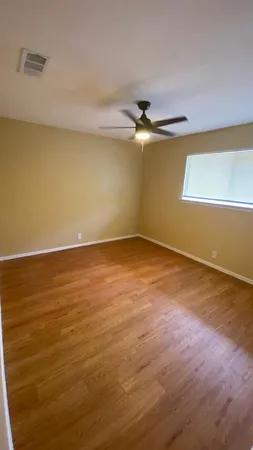 an empty room with wooden floor and fan