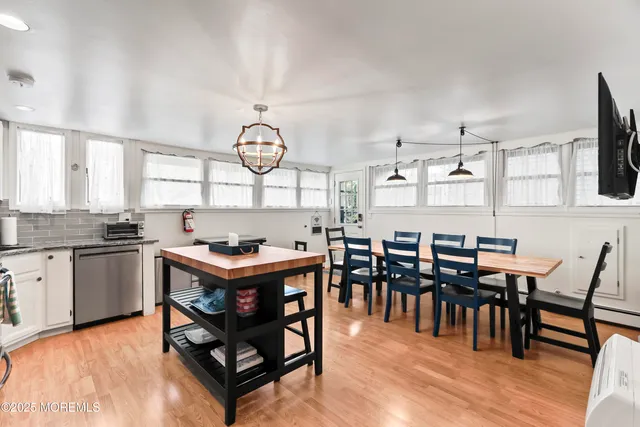 a kitchen with granite countertop a stove a sink dishwasher and a dining table with wooden floor