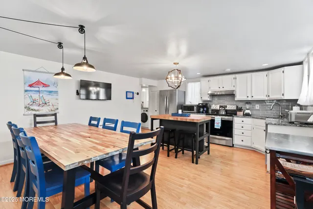 a open dining room with stainless steel appliances kitchen island granite countertop a table chairs and a kitchen view