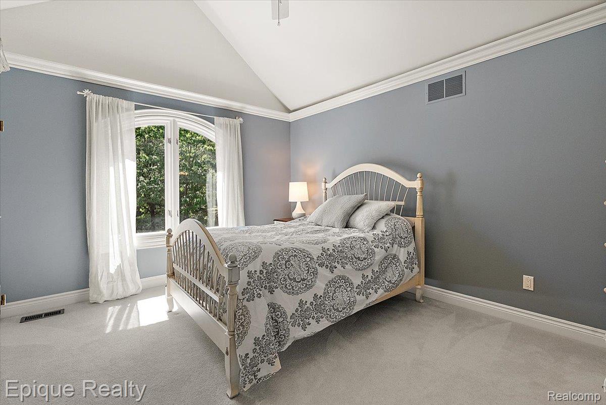 7662 Devins Ridge Clarkston, MI 48348 - Photo 67 of 81 Vaulted ceiling room featuring a large arched window, soft gray wall paint, white crown molding, and light-colored carpeting