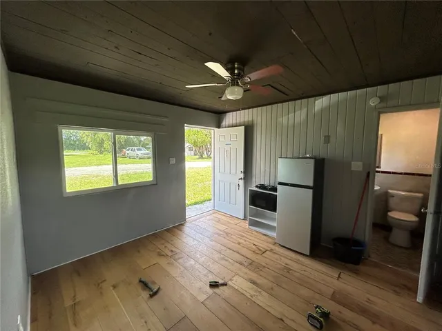 a view of a kitchen with a refrigerator a sink a ceiling fan and wooden floor