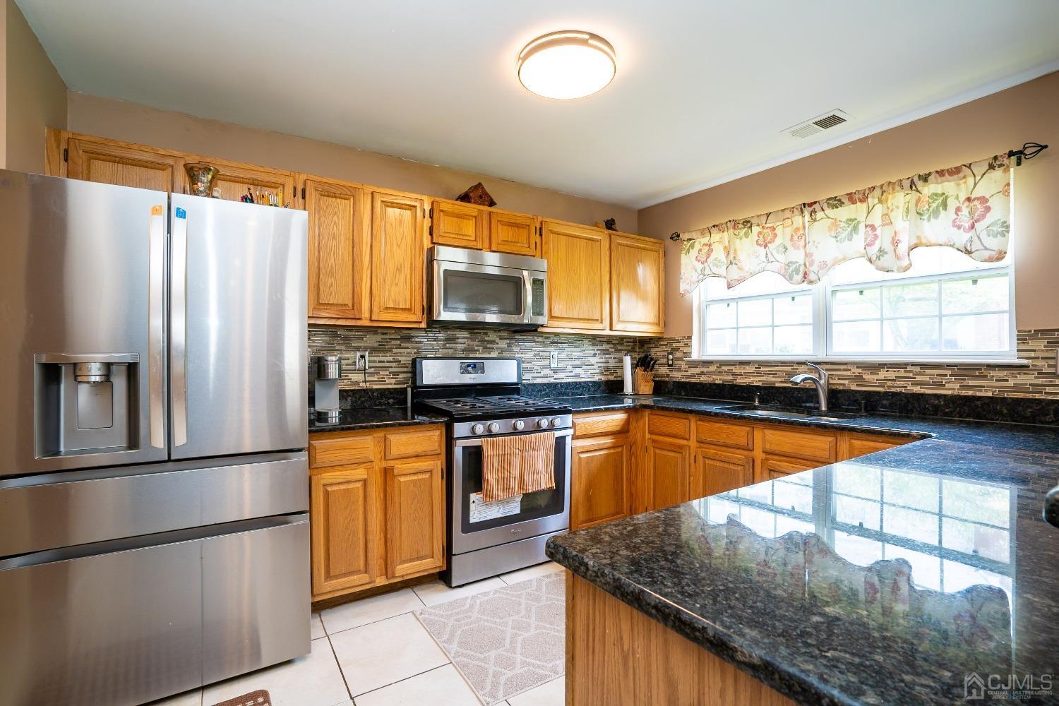 63 Springfield Road North Brunswick, NJ 08902 - Photo 13 of 42 a kitchen with stainless steel appliances granite countertop a refrigerator a sink dishwasher a stove and a microwave oven