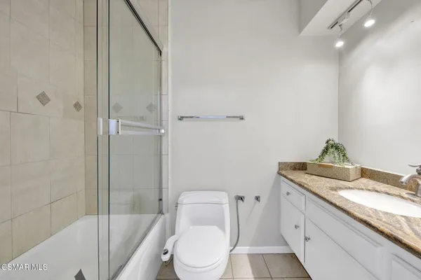 a bathroom with a granite countertop sink a toilet and shower