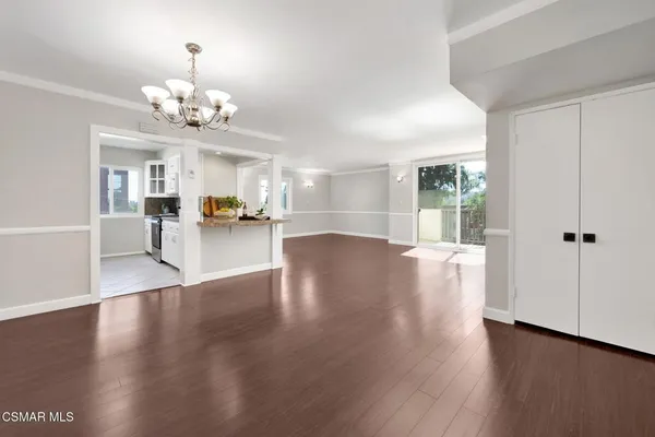 a view of a room with wooden floor and kitchen view