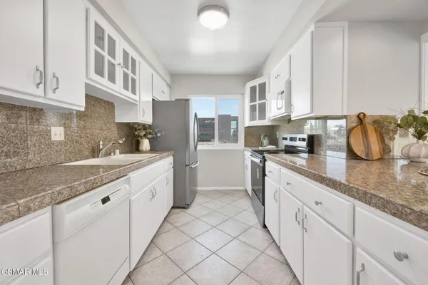 a large white kitchen with granite countertop a sink