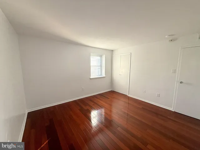 an empty room with wooden floor and window
