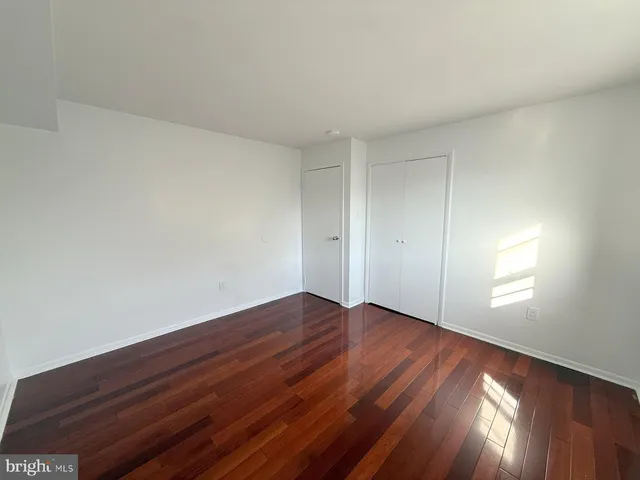 a view of an empty room with wooden floor and window