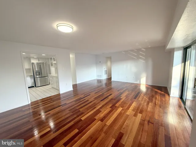 a view of empty room with wooden floor and fan
