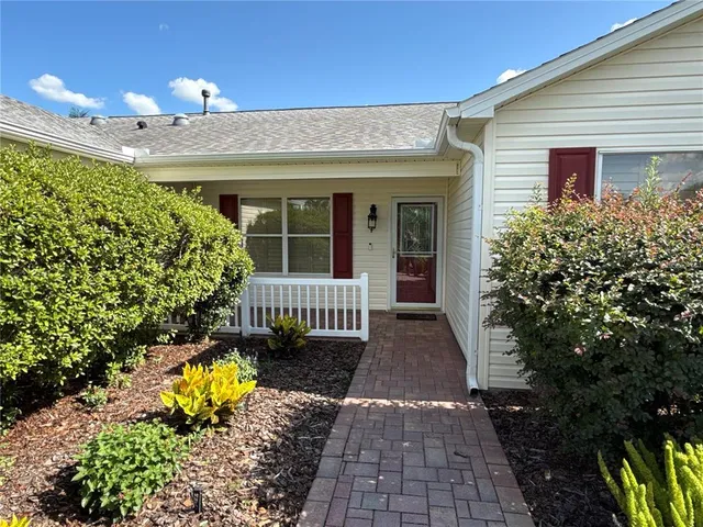 a view of a house with large trees and flower plants