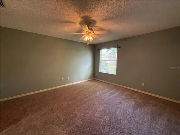an empty room with windows and fan
