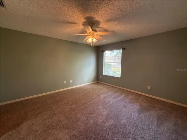 an empty room with windows and fan