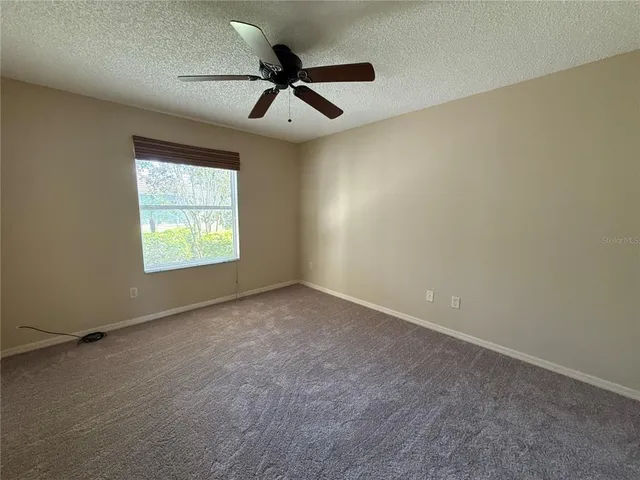 an empty room with a window and a fan