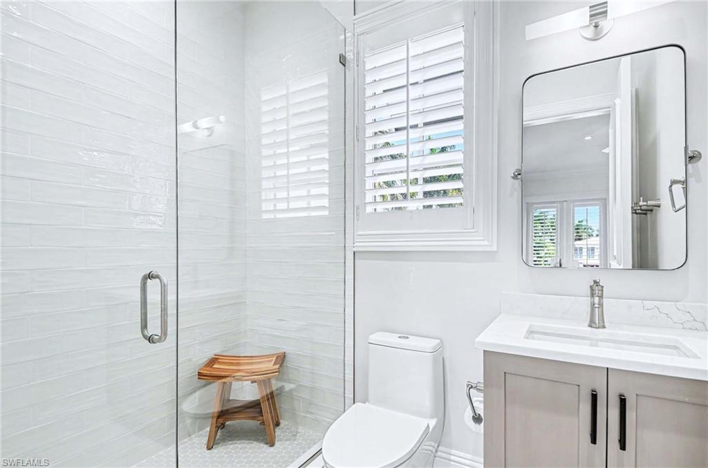 1888 6th Street South Naples, FL 34102 - Photo 28 of 37 a bathroom with a toilet a sink a mirror and a shower