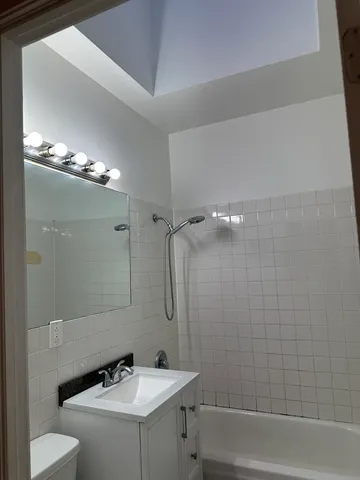a bathroom with a sink a toilet a mirror and shower