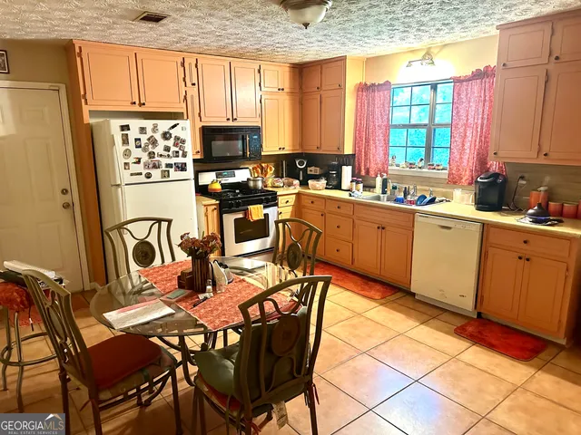 a kitchen with stainless steel appliances granite countertop a stove top oven a sink a dining table and chairs with wooden floor