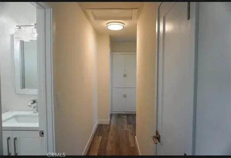 a view of an empty room with wooden floor and a bathroom