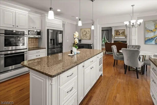 a kitchen with stainless steel appliances granite countertop a kitchen island hardwood floor sink stove dining table and chairs