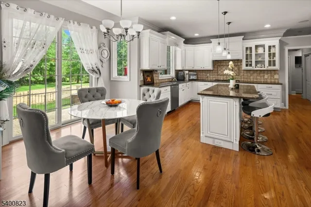 a kitchen with stainless steel appliances granite countertop a stove a refrigerator a kitchen island a dining table and chairs