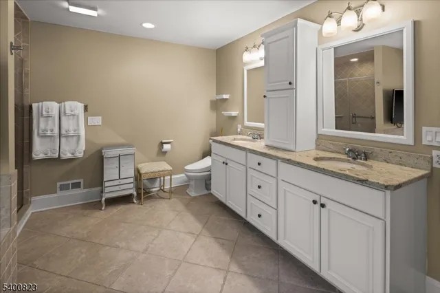 a spacious bathroom with a granite countertop sink a toilet and a mirror