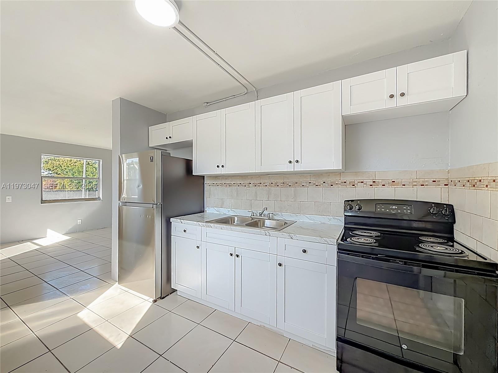 2408 Northwest 8th Street Pompano Beach, FL 33069 - Photo 3 of 24 a kitchen with granite countertop a stove sink and cabinets