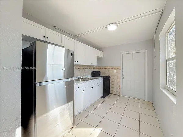a kitchen with a refrigerator a stove top oven and cabinets
