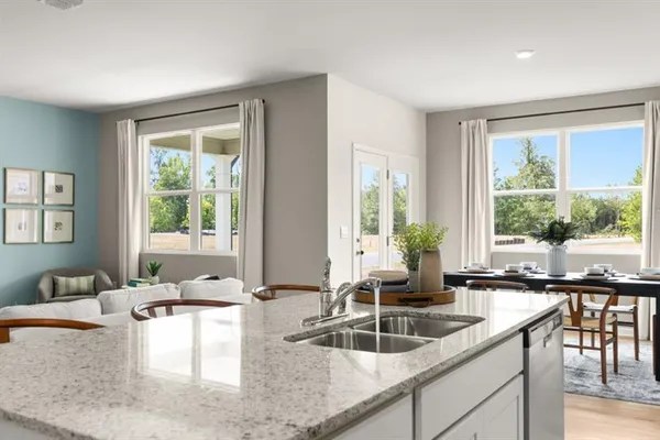 a kitchen with stainless steel appliances granite countertop a stove a sink a refrigerator a microwave a dining table and chairs