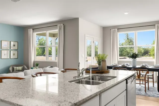 a kitchen with stainless steel appliances granite countertop a stove a sink a refrigerator a microwave a dining table and chairs