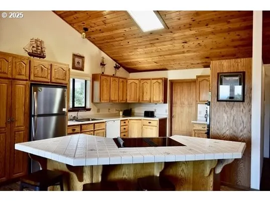 a kitchen with kitchen island granite countertop a sink cabinets and stainless steel appliances