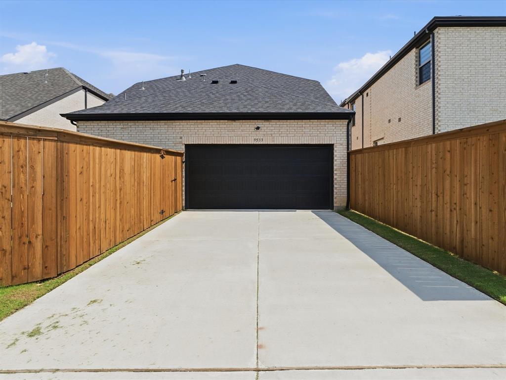 9533 Keep Street Frisco, TX 75035 - Photo 37 of 40 Rear-entry garage with an asphalt shingle roof and light-colored brick exterior