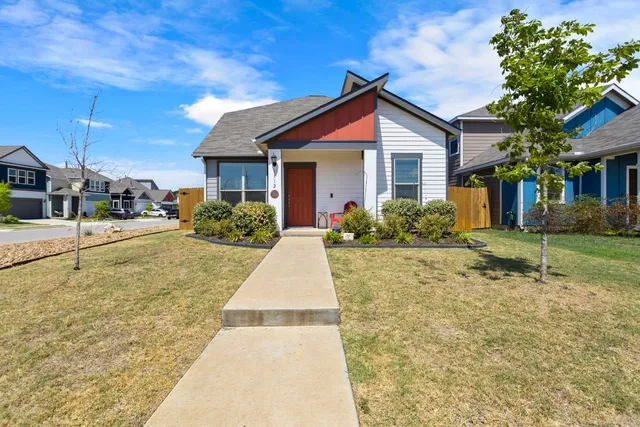 a view of a house with cars park side of road