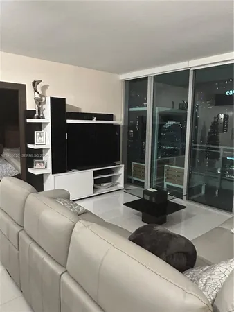 a living room with furniture a flat screen tv and a floor to ceiling window