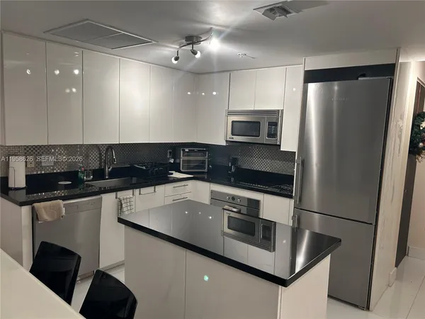 a kitchen with stainless steel appliances a sink a stove a microwave a refrigerator a counter space and cabinets