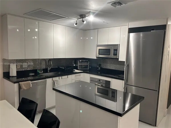 a kitchen with stainless steel appliances granite countertop a refrigerator a stove a sink and a microwave