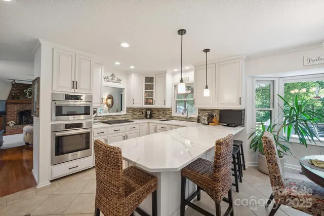 a large kitchen with granite countertop lots of white cabinets and white appliances