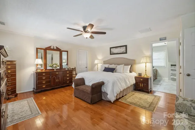 a bedroom with a bed a dresser and wooden floor