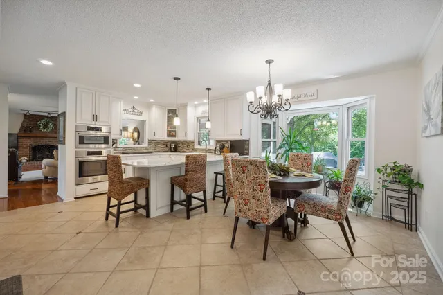 a kitchen with stainless steel appliances kitchen island granite countertop a stove a sink a oven a dining table and chairs