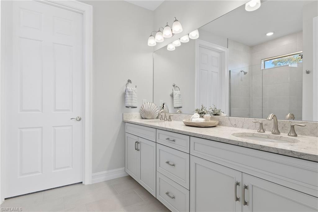 318 Deauville Loop Naples, FL 34114 - Photo 16 of 21 a bathroom with double vanity sinks a vanity a lamp and a mirror