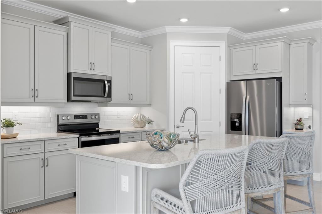 318 Deauville Loop Naples, FL 34114 - Photo 9 of 21 a kitchen with stainless steel appliances granite countertop a stove a sink a microwave a refrigerator and white cabinets