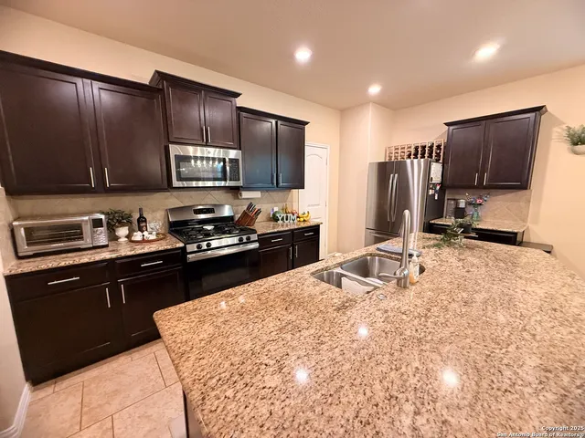 a kitchen with stainless steel appliances kitchen island granite countertop a refrigerator stove and sink