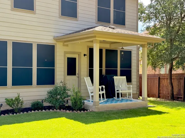 a view of a house with a yard plants and large tree