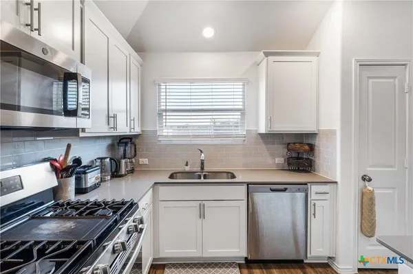 a kitchen with granite countertop a stove sink and cabinets